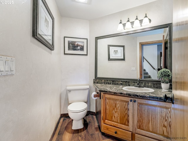 bathroom with toilet, vanity, and wood finished floors