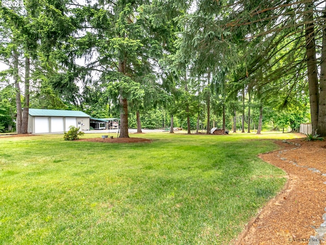 view of yard with a garage and an outbuilding