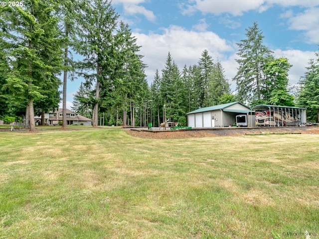 view of yard featuring a detached garage, playground community, and an outdoor structure