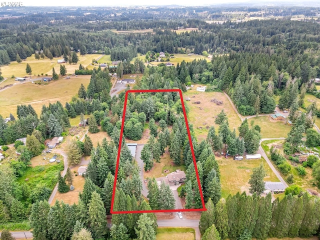 birds eye view of property featuring a rural view and a wooded view