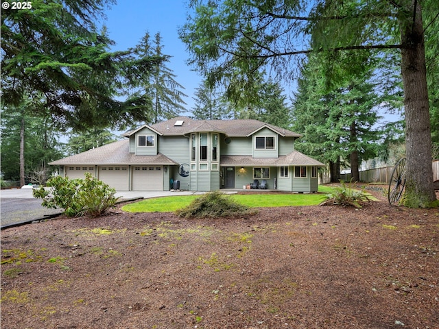 view of front of house featuring fence, driveway, roof with shingles, covered porch, and a garage