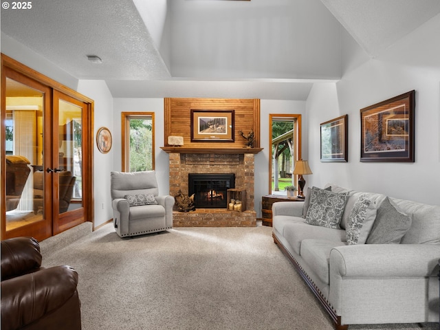 carpeted living room featuring lofted ceiling, french doors, a wealth of natural light, and a large fireplace