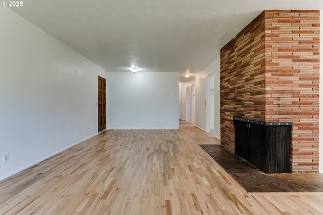 2220 Hayes St, Eugene, OR 97405 - unfurnished living room with wood finished floors, a brick fireplace, and baseboards