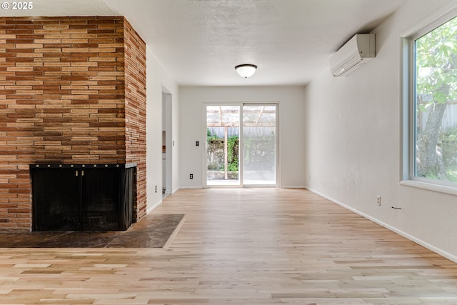 2220 Hayes St, Eugene, OR 97405 - unfurnished living room featuring a wall mounted AC, wood finished floors, baseboards, and a brick fireplace