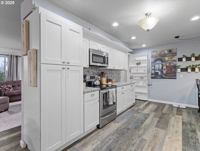 kitchen featuring appliances with stainless steel finishes, white cabinetry, light stone counters, dark hardwood / wood-style flooring, and decorative backsplash