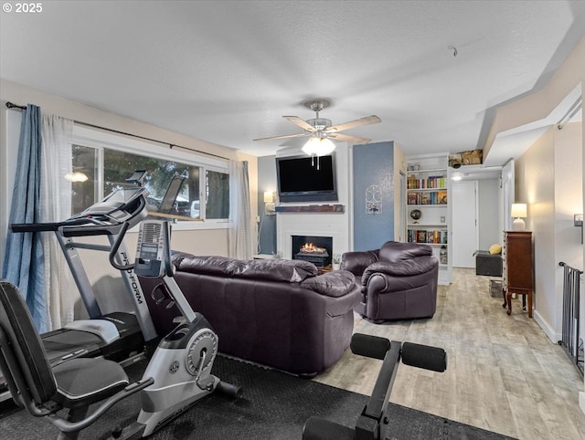 workout room featuring ceiling fan, a textured ceiling, and light hardwood / wood-style floors