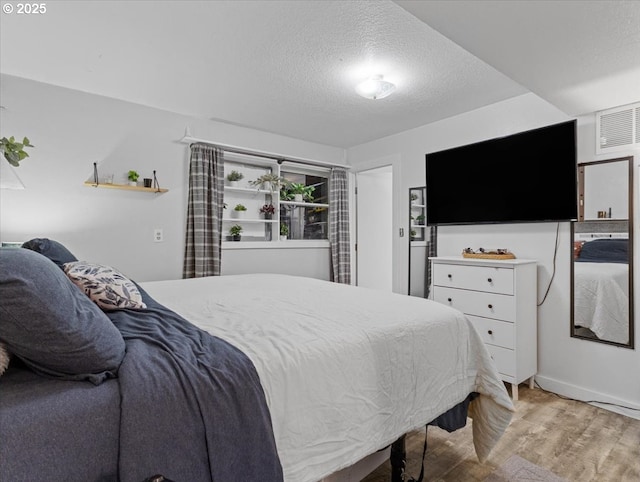 bedroom with a textured ceiling and light wood-type flooring