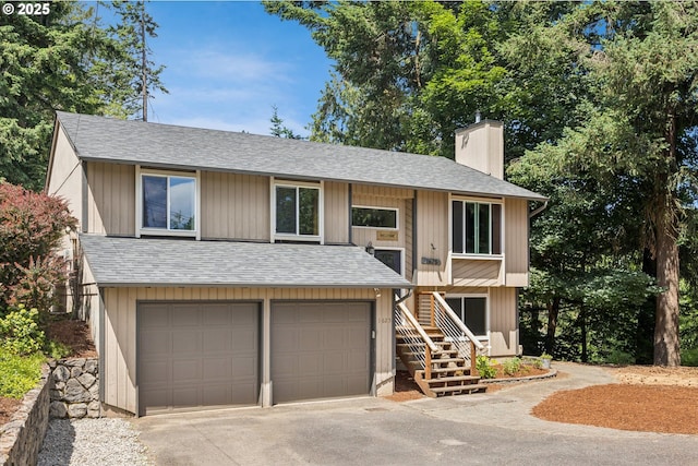 1625 SE Regner Rd, Gresham, OR 97080 - split foyer home with an attached garage, a chimney, a shingled roof, stairs, and driveway