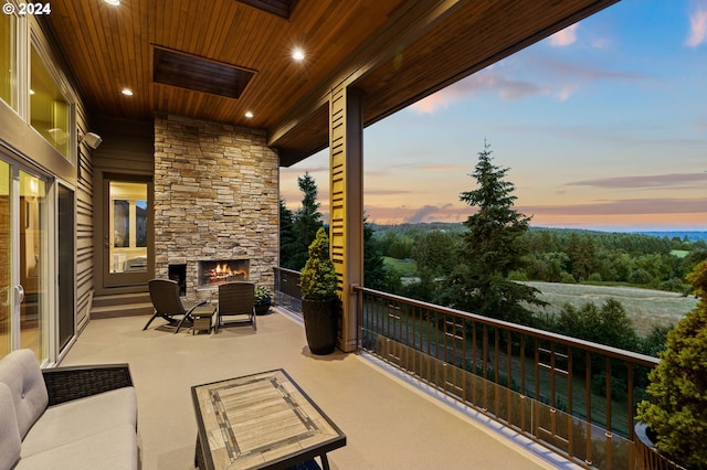 balcony at dusk with an outdoor stone fireplace