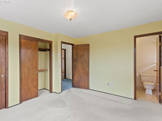 bedroom featuring light carpet, a textured ceiling, and ensuite bathroom