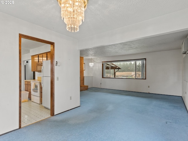 carpeted spare room with a textured ceiling and a chandelier