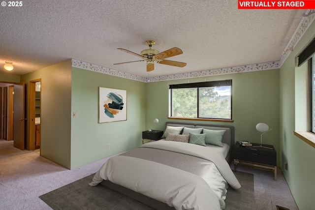 bedroom featuring carpet flooring, a ceiling fan, and a textured ceiling