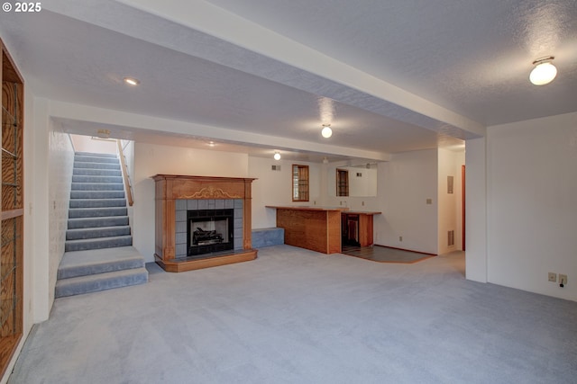 unfurnished living room with a fireplace, carpet floors, a textured ceiling, indoor wet bar, and stairway