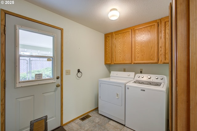 washroom featuring visible vents, washer and clothes dryer, cabinet space, and baseboards