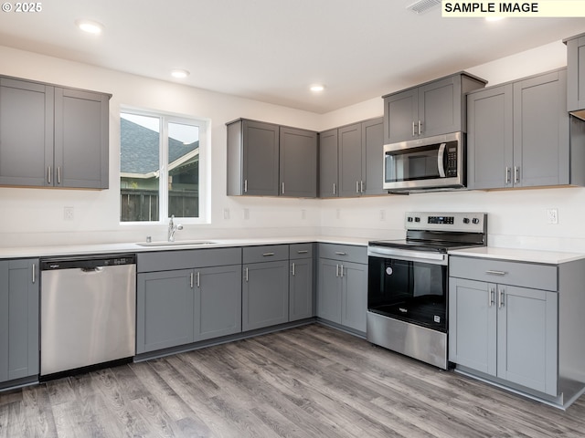 5416 NE 66th Pl, Vancouver, WA 98661 - kitchen with appliances with stainless steel finishes, gray cabinetry, a sink, light wood-type flooring, and recessed lighting
