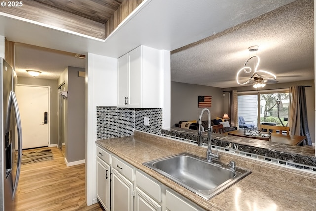 kitchen with white cabinetry, sink, stainless steel fridge, and light hardwood / wood-style floors