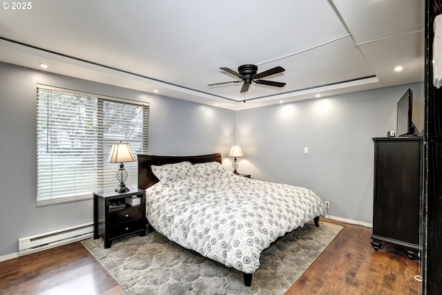 bedroom featuring dark hardwood / wood-style flooring, a tray ceiling, ceiling fan, and baseboard heating