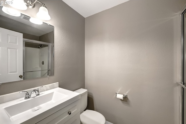 bathroom featuring vanity, a shower with door, and toilet