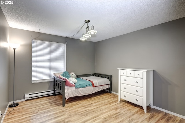 bedroom featuring a baseboard radiator, light hardwood / wood-style flooring, and a textured ceiling