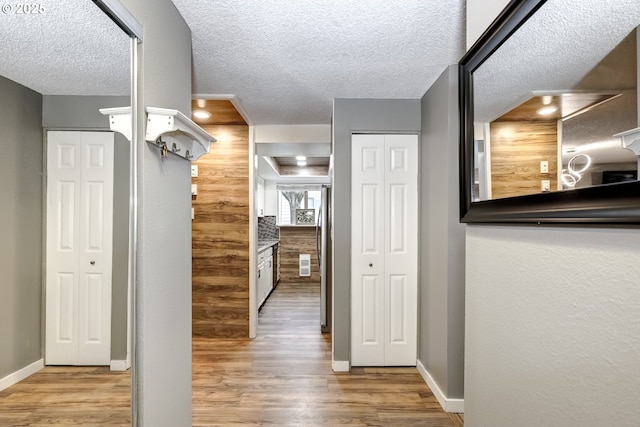 corridor featuring a textured ceiling and light wood-type flooring