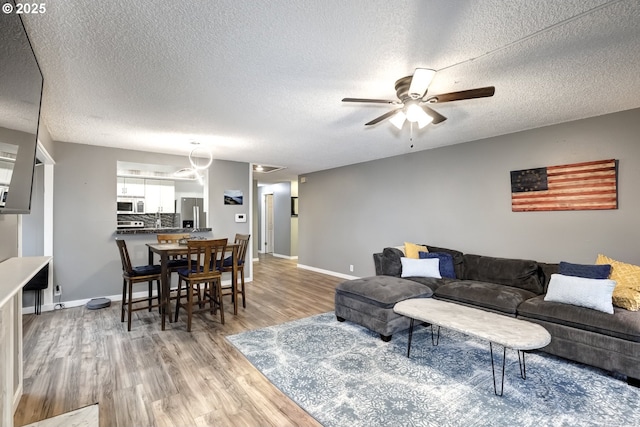 living room with ceiling fan, hardwood / wood-style floors, and a textured ceiling