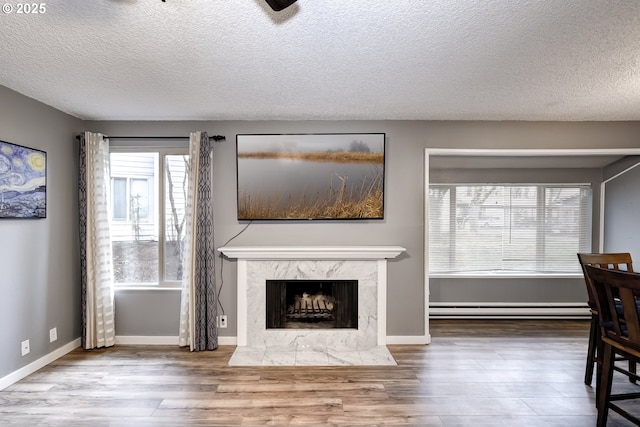 unfurnished living room with hardwood / wood-style flooring, a high end fireplace, a textured ceiling, and baseboard heating