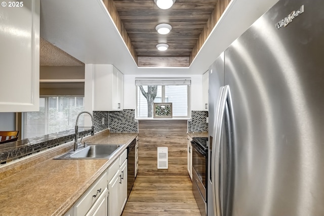 kitchen featuring stainless steel appliances, a raised ceiling, sink, and white cabinets