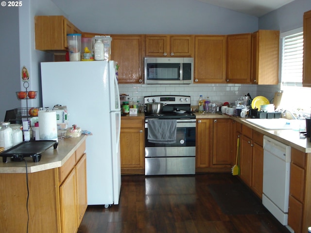 131 NW Makah Ct, Roseburg, OR 97471 - kitchen with stainless steel appliances, a sink, vaulted ceiling, dark wood-type flooring, and tasteful backsplash