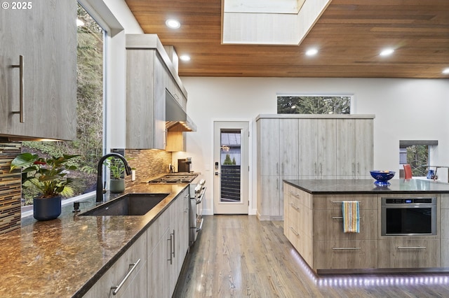 kitchen with modern cabinets, a sink, dark stone counters, appliances with stainless steel finishes, and wooden ceiling
