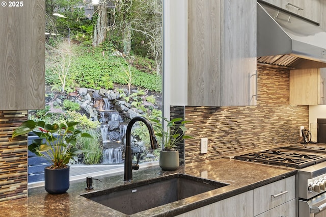 kitchen with stainless steel gas stove, modern cabinets, under cabinet range hood, and a sink