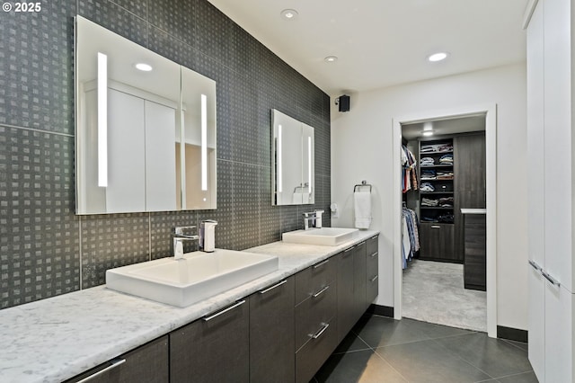 full bath with tile patterned floors, double vanity, a spacious closet, and a sink