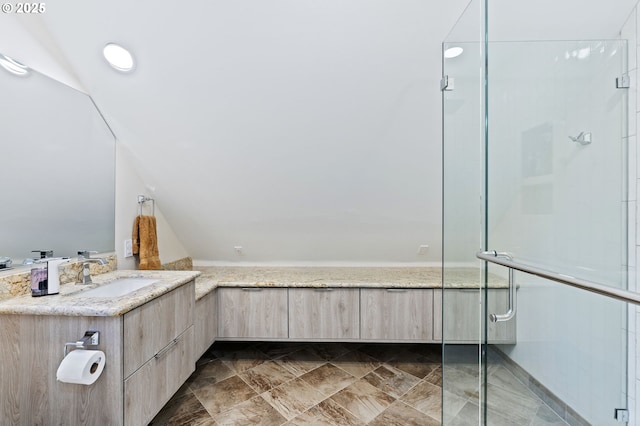 full bathroom with a stall shower, vanity, and lofted ceiling