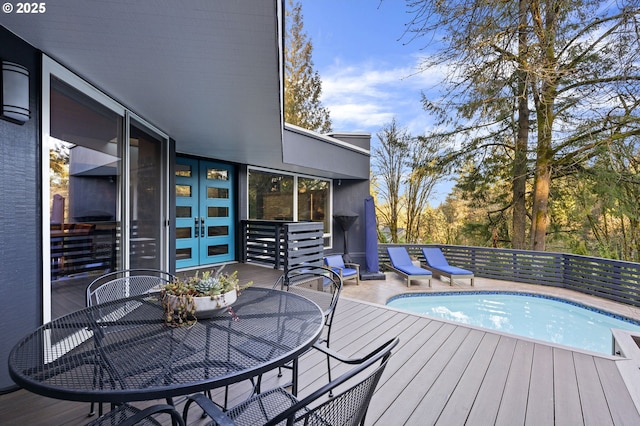 wooden deck featuring a fenced in pool, french doors, and outdoor dining area