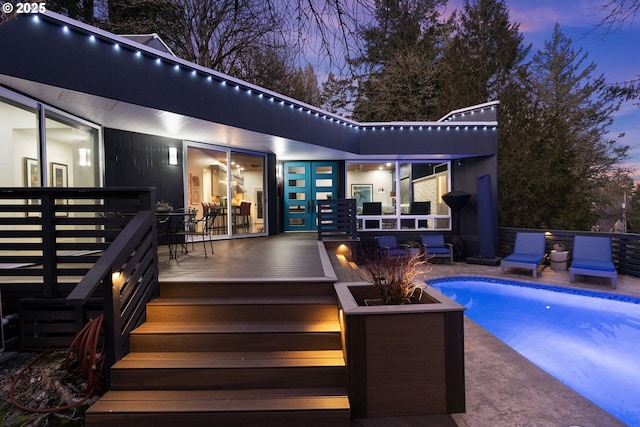 back of property with a deck and an outdoor pool