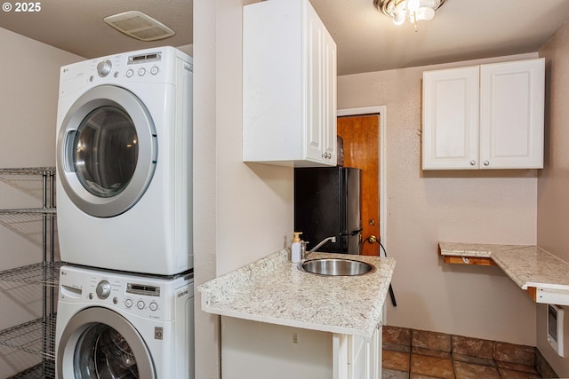 clothes washing area with estacked washer and dryer and cabinet space
