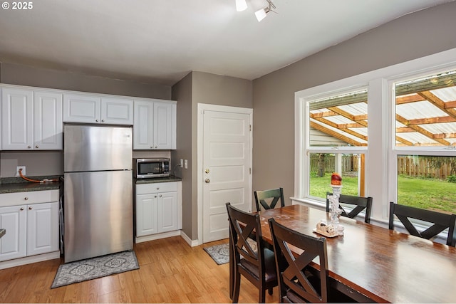 kitchen featuring appliances with stainless steel finishes, light wood-type flooring, white cabinets, and dark countertops