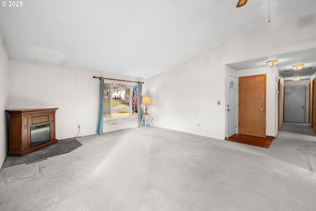 unfurnished living room with ceiling fan, lofted ceiling, light colored carpet, and a textured ceiling