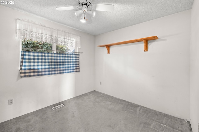 empty room featuring ceiling fan, carpet, and a textured ceiling