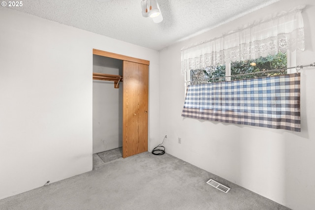 unfurnished bedroom featuring light colored carpet, a closet, and a textured ceiling