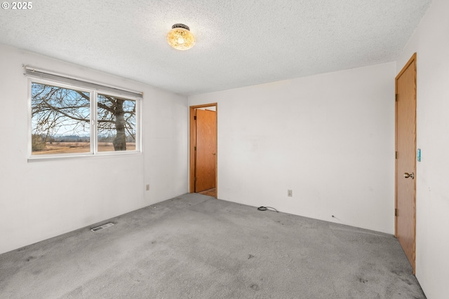 empty room with light colored carpet and a textured ceiling