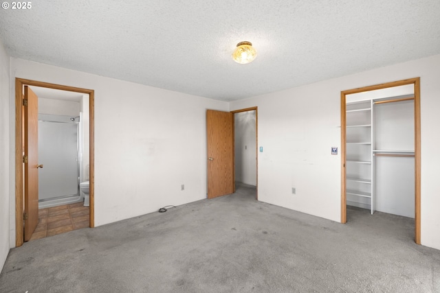 unfurnished bedroom with light carpet, a closet, a textured ceiling, and ensuite bathroom