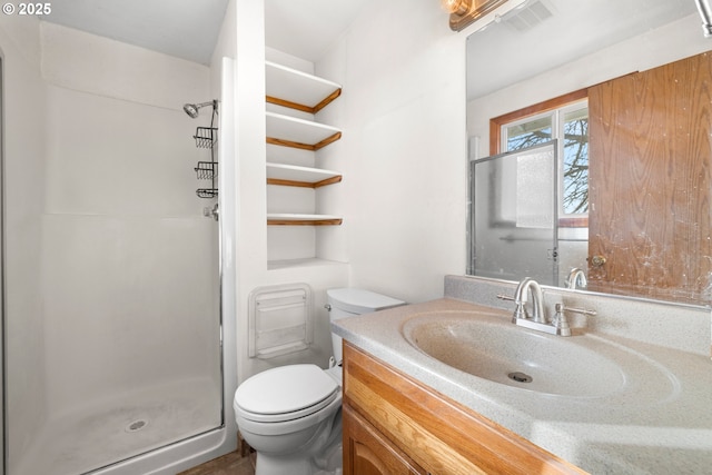 bathroom with vanity, a shower with door, and toilet