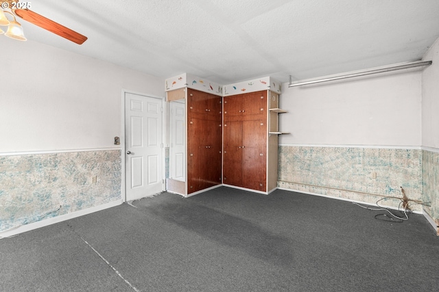 carpeted empty room with ceiling fan and a textured ceiling