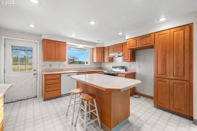 kitchen with a kitchen bar, sink, a center island, white dishwasher, and electric stove