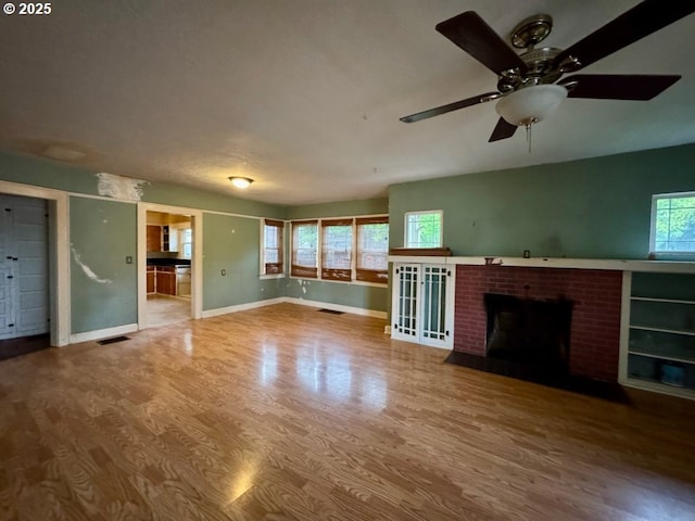 unfurnished living room with ceiling fan, a fireplace, and wood-type flooring