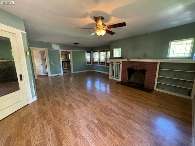 unfurnished living room featuring hardwood / wood-style flooring, ceiling fan, and a fireplace