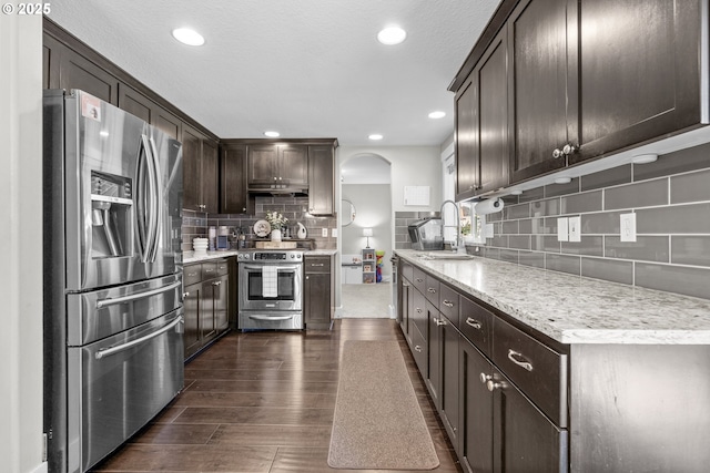 1366 Cramner St, Lafayette, OR 97127 - kitchen with stainless steel appliances, backsplash, dark brown cabinets, a sink, and arched walkways