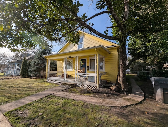 bungalow featuring a front lawn, fence, and covered porch