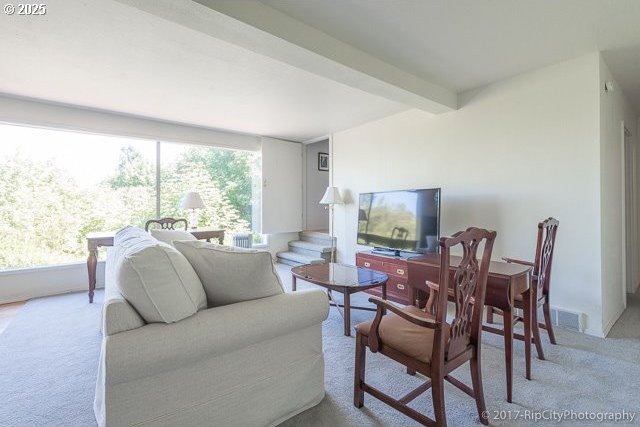 carpeted living room featuring beamed ceiling