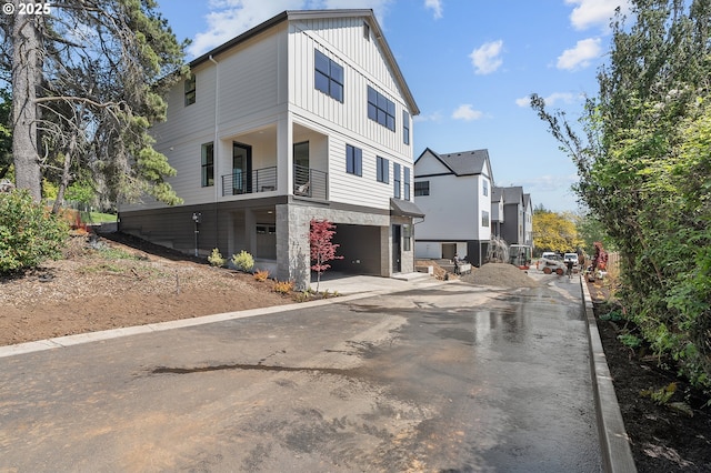 exterior space featuring board and batten siding, a balcony, and a garage